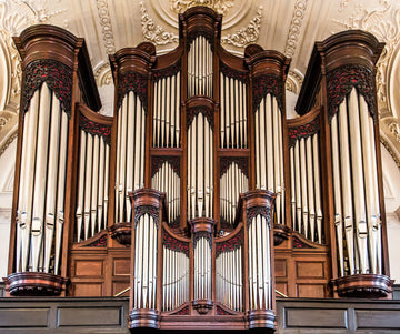 A grand pipe organ with gleaming silver pipes and an ornate case in a church sanctuary